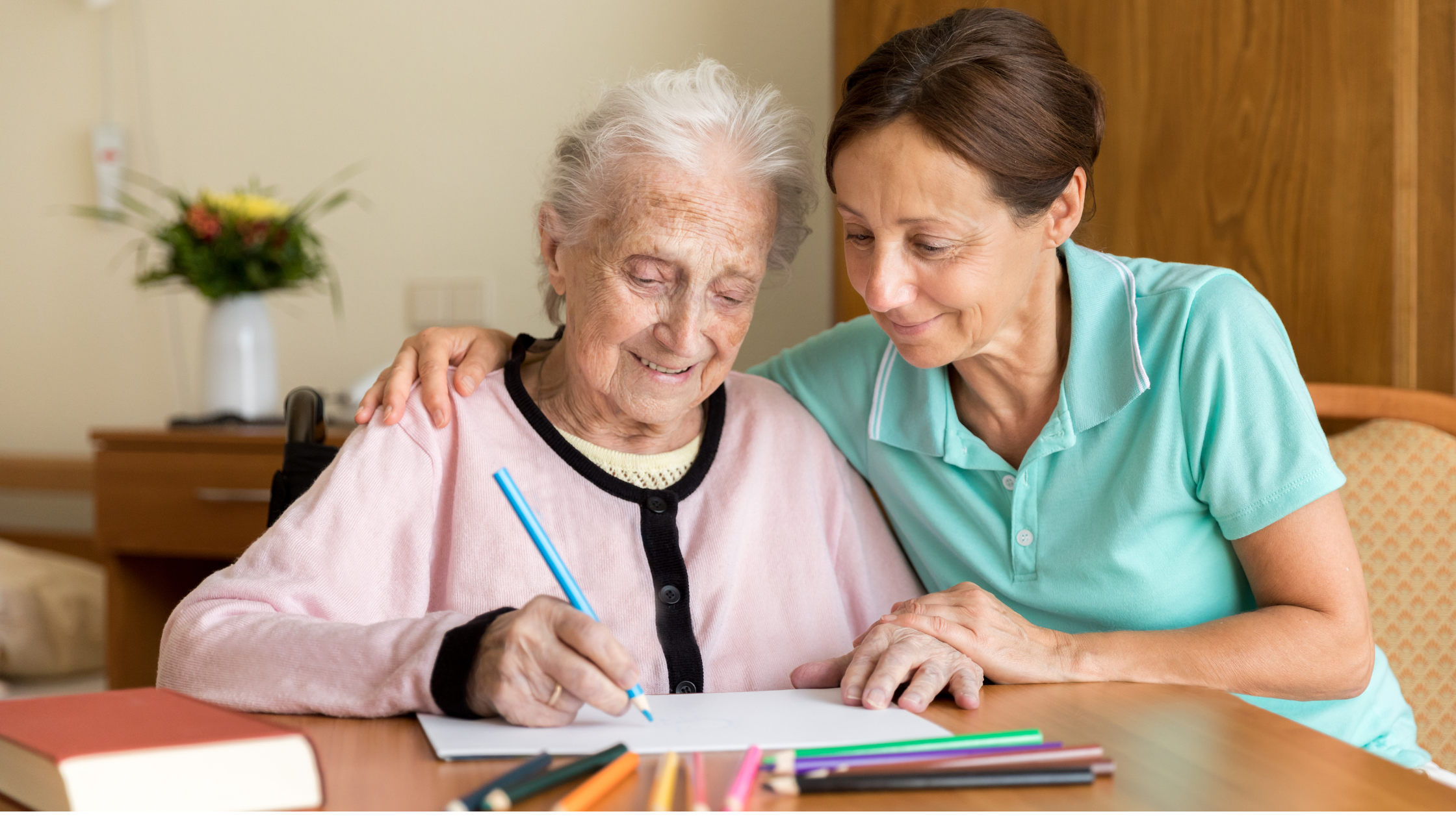 An elderly adult practicing writing with support from an occupational therapist.